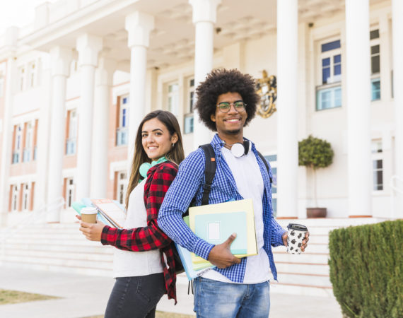Diverse young male female student holding books takeaway coffee cup standing front building
