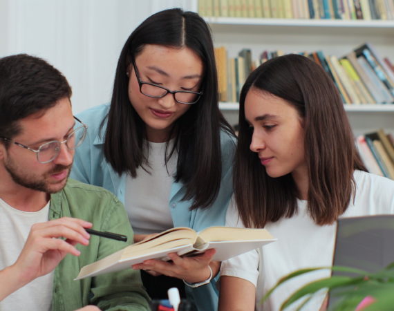 Happy multi ethnic college students smiling look at camera, posing in modern university library. Education, study, modern tech concept.